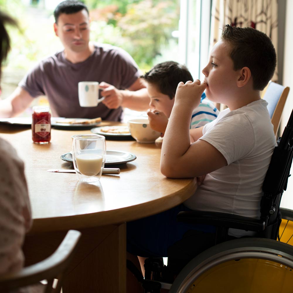 Photo of family dining with young person in a wheelchair