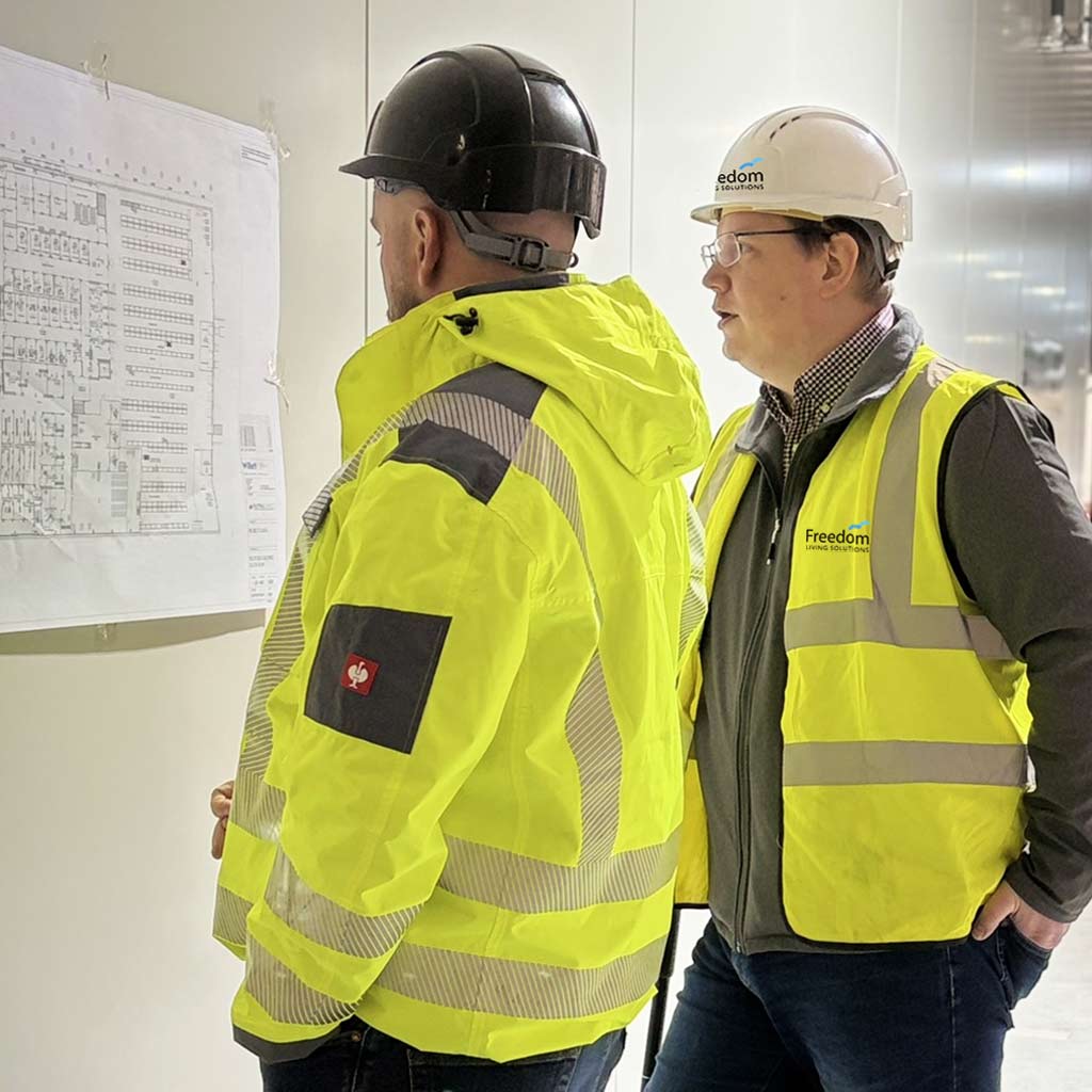 Freedom team working on site Two Freedom construction team members on site reviewing a construction plan together.